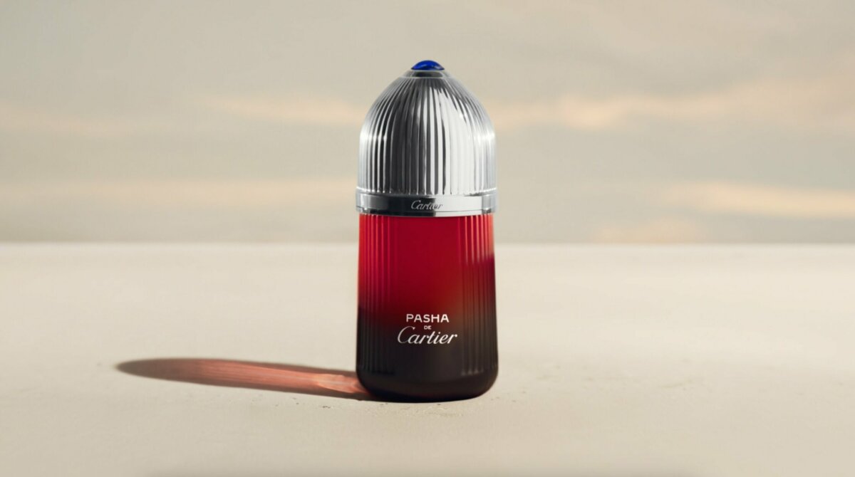 Pasha de Cartier fragrance bottle in red on a minimal sand set – Cartier Parfums