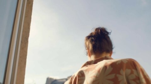 Woman wrapped in a blanket at a sunlit window – Oh My Cream portrait